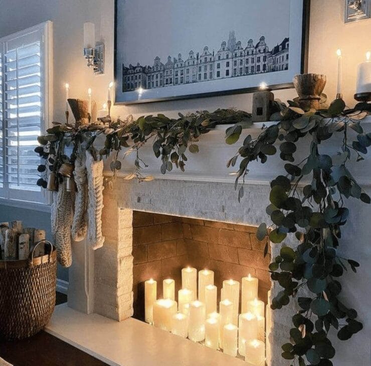 some lighted candles on a decorated winter fireplace mantel